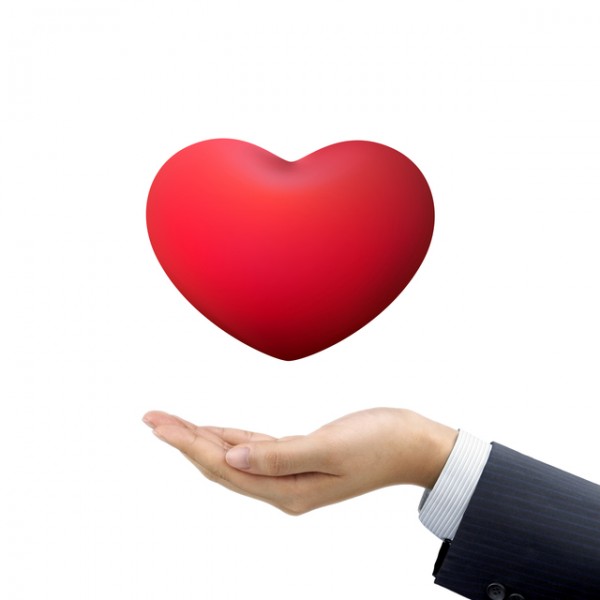businessman's hand holding red heart symbol over white background